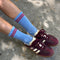 model wearing blue socks with two red stripes on the top with maroon sneakers on