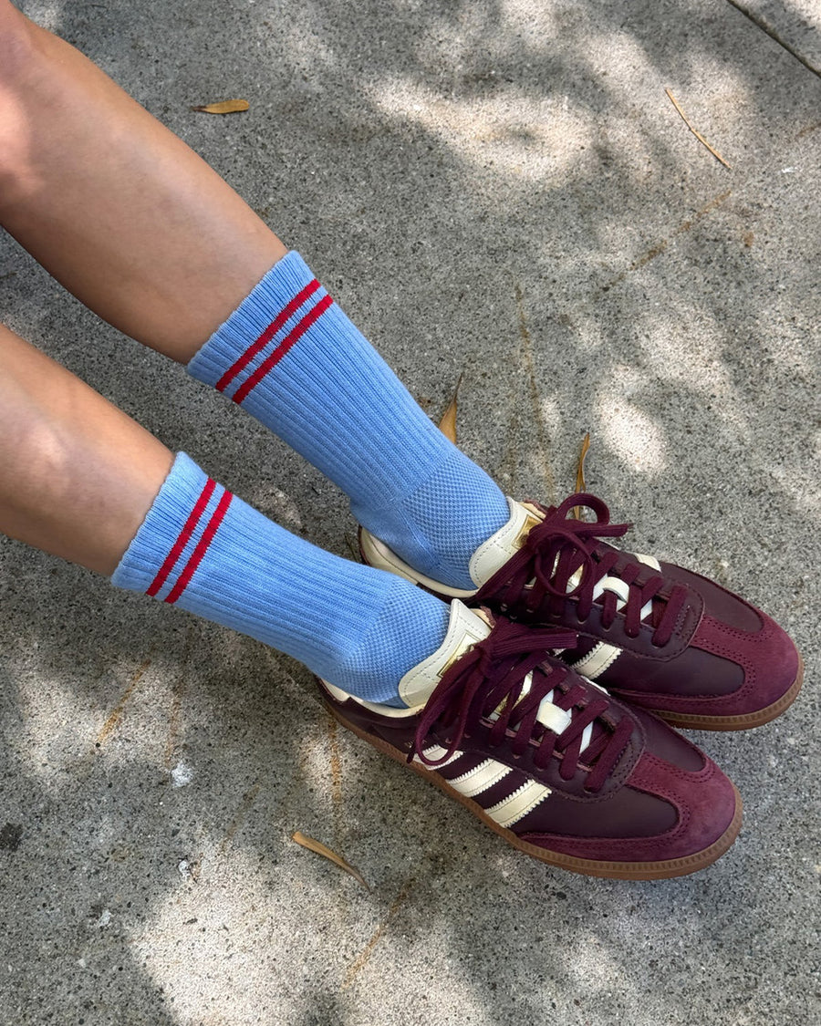 model wearing blue socks with two red stripes on the top with maroon sneakers on