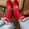 model wearing red tube socks with two white stripe detail