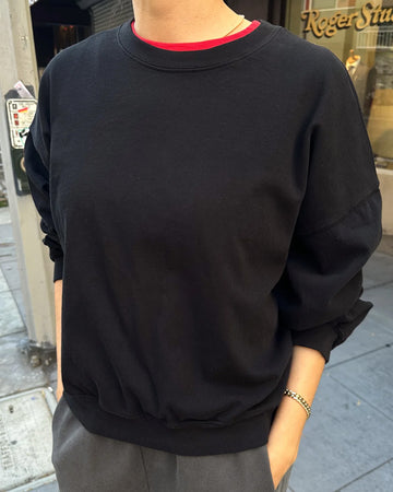 model wearing black crewneck sweatshirt with drop sleeves and banded bottom