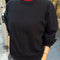 model wearing black crewneck sweatshirt with drop sleeves and banded bottom