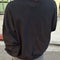 back view of model wearing black crewneck sweatshirt with drop sleeves and banded bottom