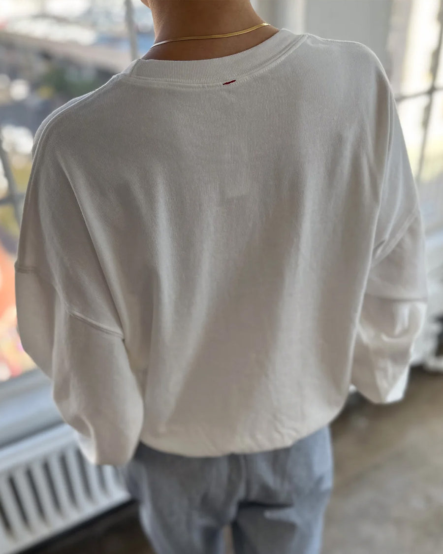 back view of model wearing vintage white crewneck sweatshirt with drop sleeves and banded bottom