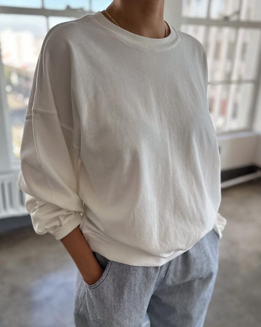 model wearing vintage white crewneck sweatshirt with drop sleeves and banded bottom