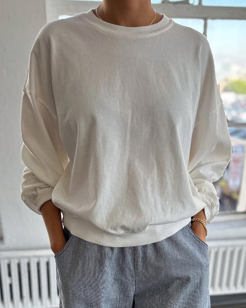 model wearing vintage white crewneck sweatshirt with drop sleeves and banded bottom