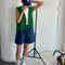 model wearing denim shorts with pockets and elastic waist with green knit vest, white top, and baseball cap