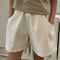 up close of model wearing cream cotton shorts with pockets and elastic waistband