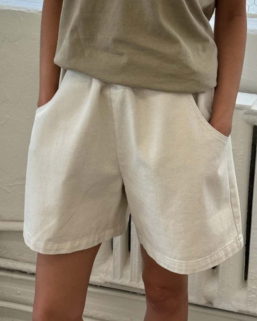 up close of model wearing cream cotton shorts with pockets and elastic waistband