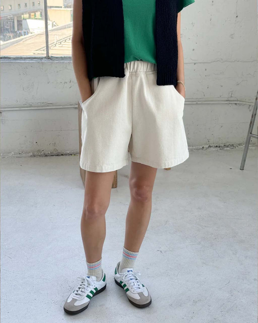 model wearing cream cotton shorts with pockets and elastic waistband