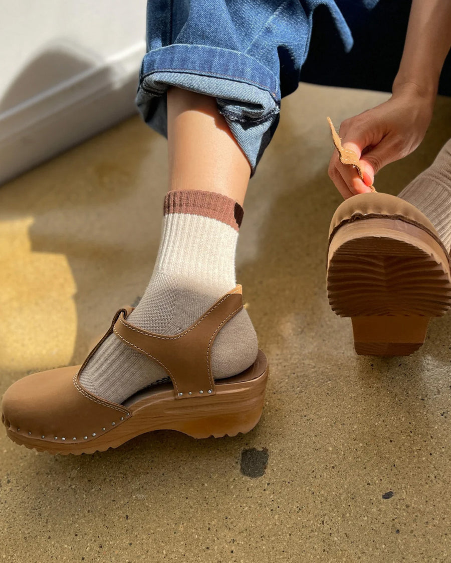 model wearing cream crew socks with brown and black trim and sandals