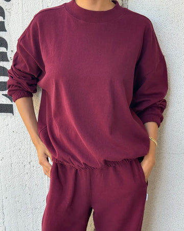 model wearing cabernet colored long sleeve mock neck top with elastic hem