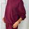 side view of model wearing cabernet colored long sleeve mock neck top with elastic hem