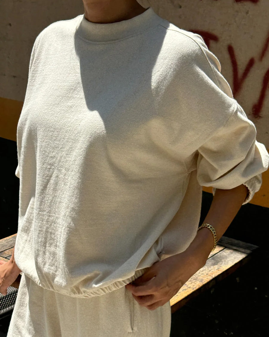 side view of model wearing naturel colored long sleeve mock neck top with elastic hem