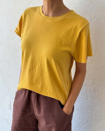 model wearing golden yellow relaxed tee with slight distressing on neckline and sleeves