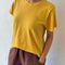 model wearing golden yellow relaxed tee with slight distressing on neckline and sleeves