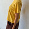 side view of model wearing golden yellow relaxed tee with slight distressing on neckline and sleeves