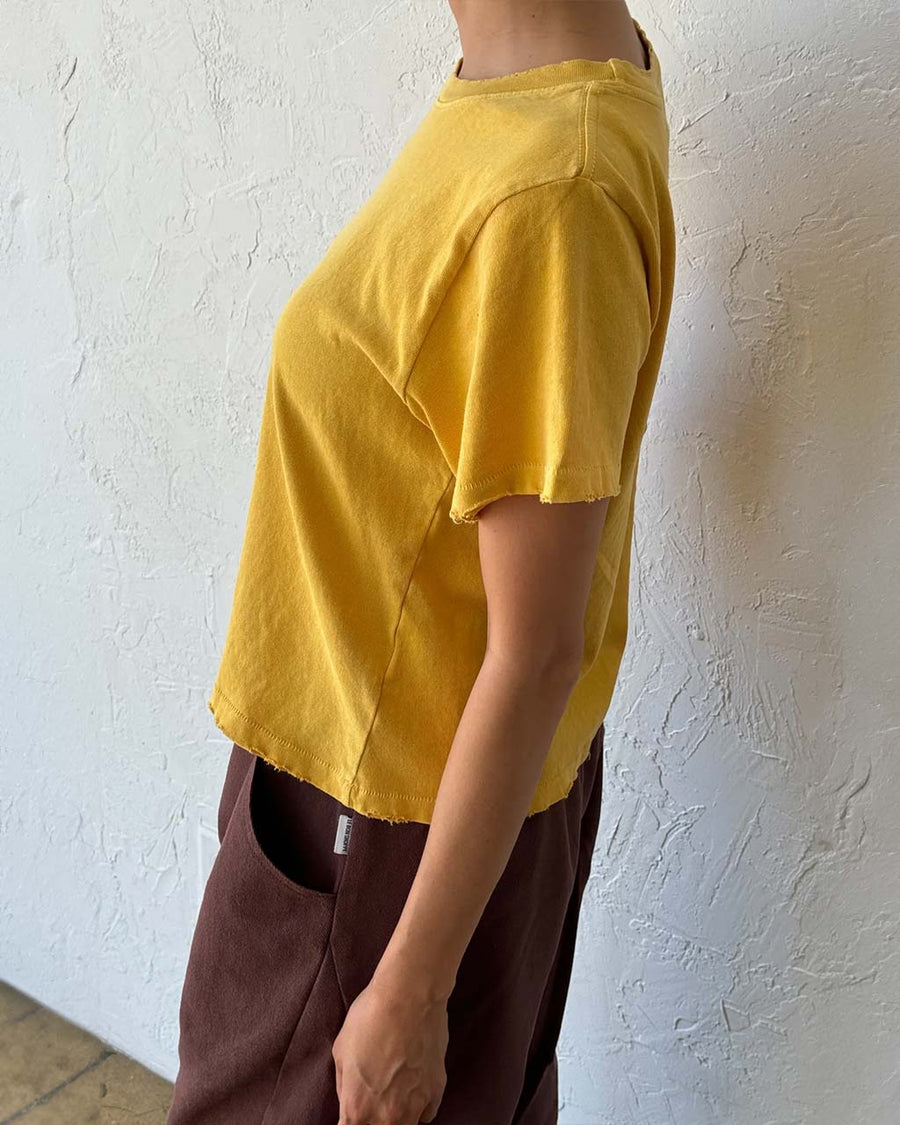 side view of model wearing golden yellow relaxed tee with slight distressing on neckline and sleeves