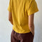 back view of model wearing golden yellow relaxed tee with slight distressing on neckline and sleeves