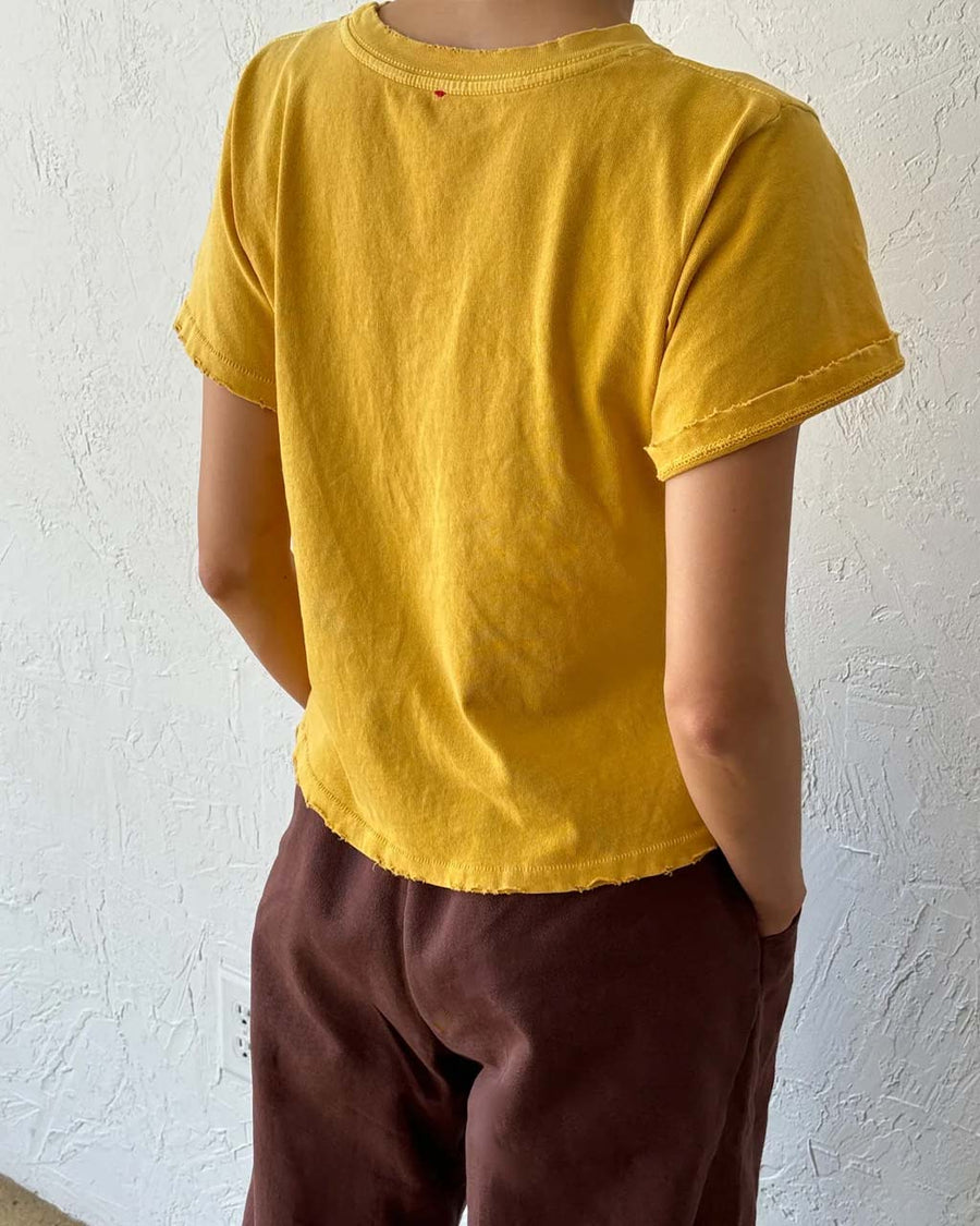 back view of model wearing golden yellow relaxed tee with slight distressing on neckline and sleeves