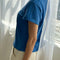 side view of model wearing relaxed fit cobalt blue cotton tee with slight distressing on the neckline and sleeves