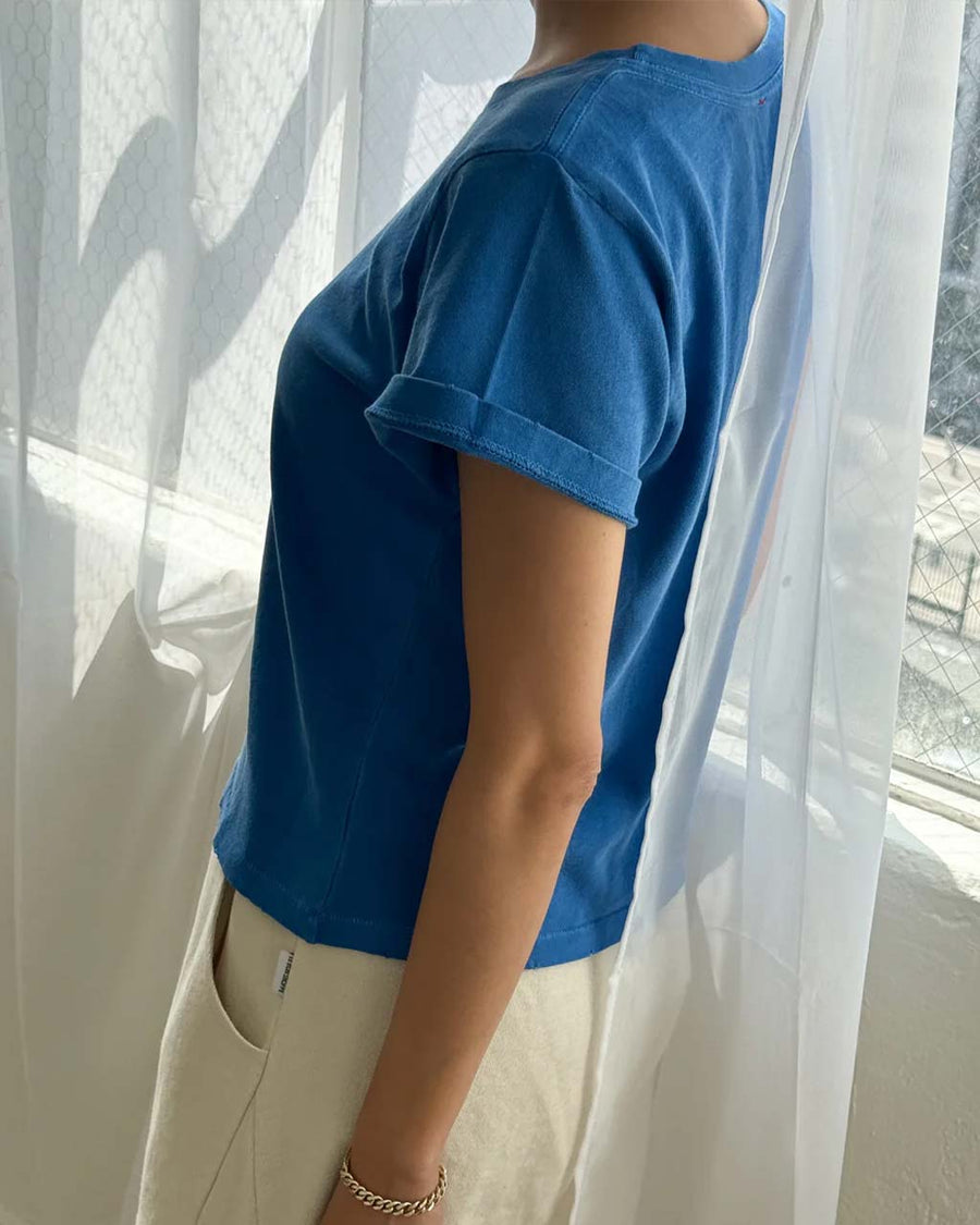 side view of model wearing relaxed fit cobalt blue cotton tee with slight distressing on the neckline and sleeves