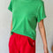 model wearing emerald green relaxed tee with slight distressing on neckline and sleeves