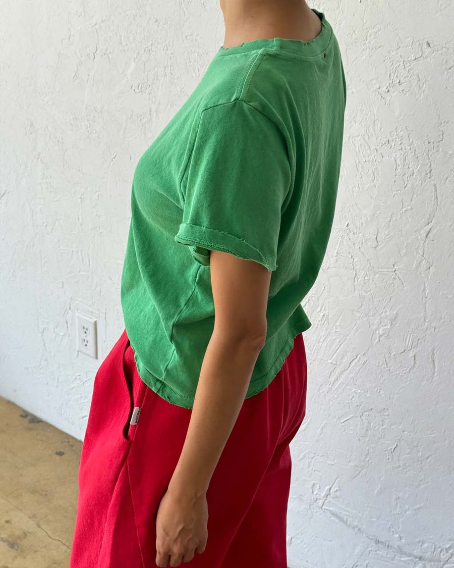 side view of model wearing emerald green relaxed tee with slight distressing on neckline and sleeves