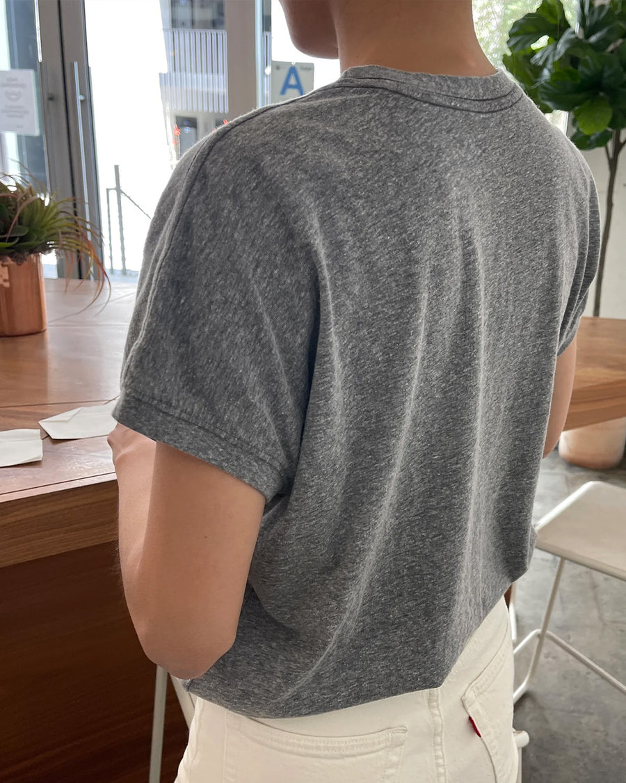 back view of model wearing heather grey top with slight cap sleeves and relaxed fit