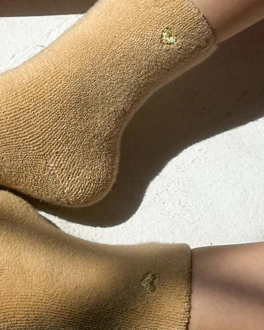 up close of model wearing fuzzy tan socks with gold metallic heart detail