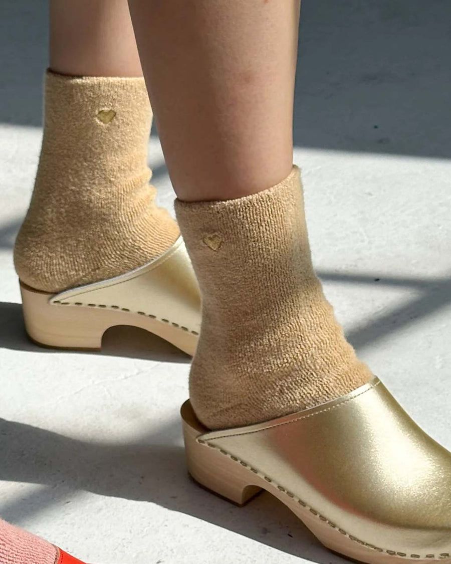 model wearing fuzzy tan socks with gold metallic heart detail