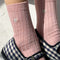 up close of model wearing light pink ribbed socks with silver seashell detail