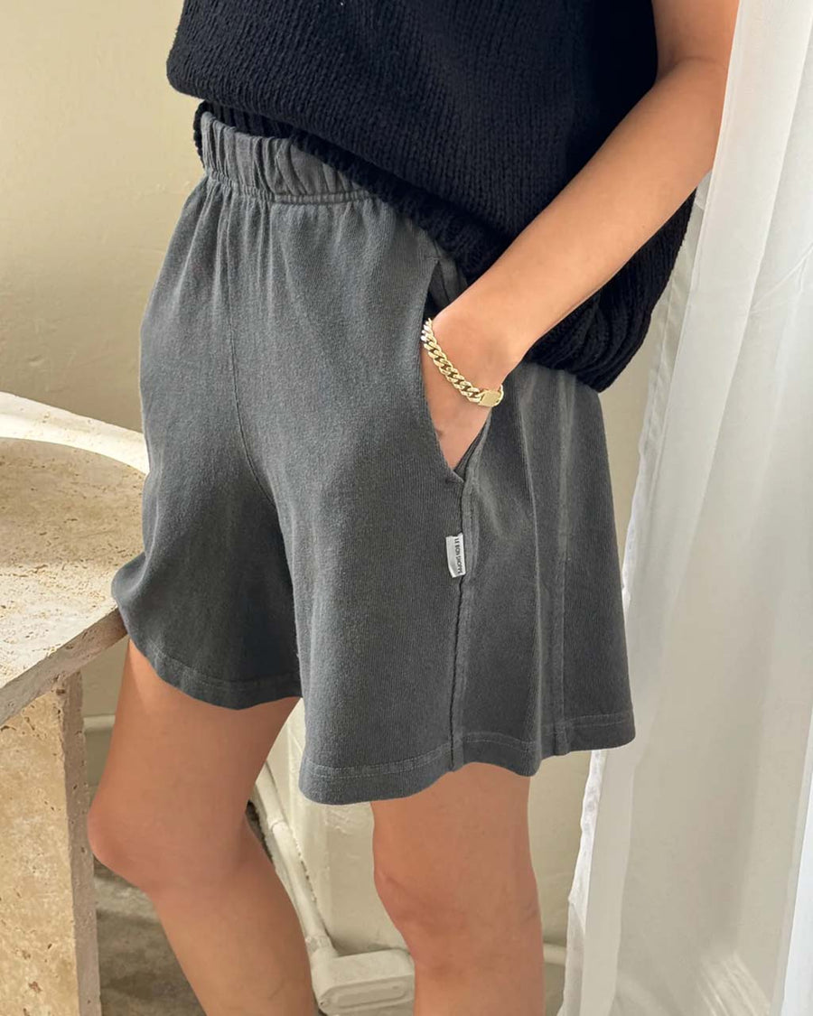 side view of model wearing coal flared cotton basketball shorts with pockets