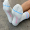 bottom view of model wearing heather grey socks with light blue and light pink stripes on the top