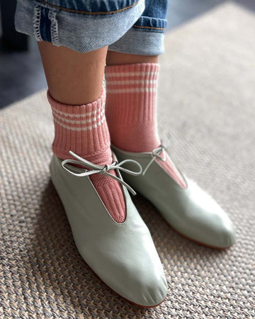 model wearing salmon high crew socks with three white stripes at the top with flats