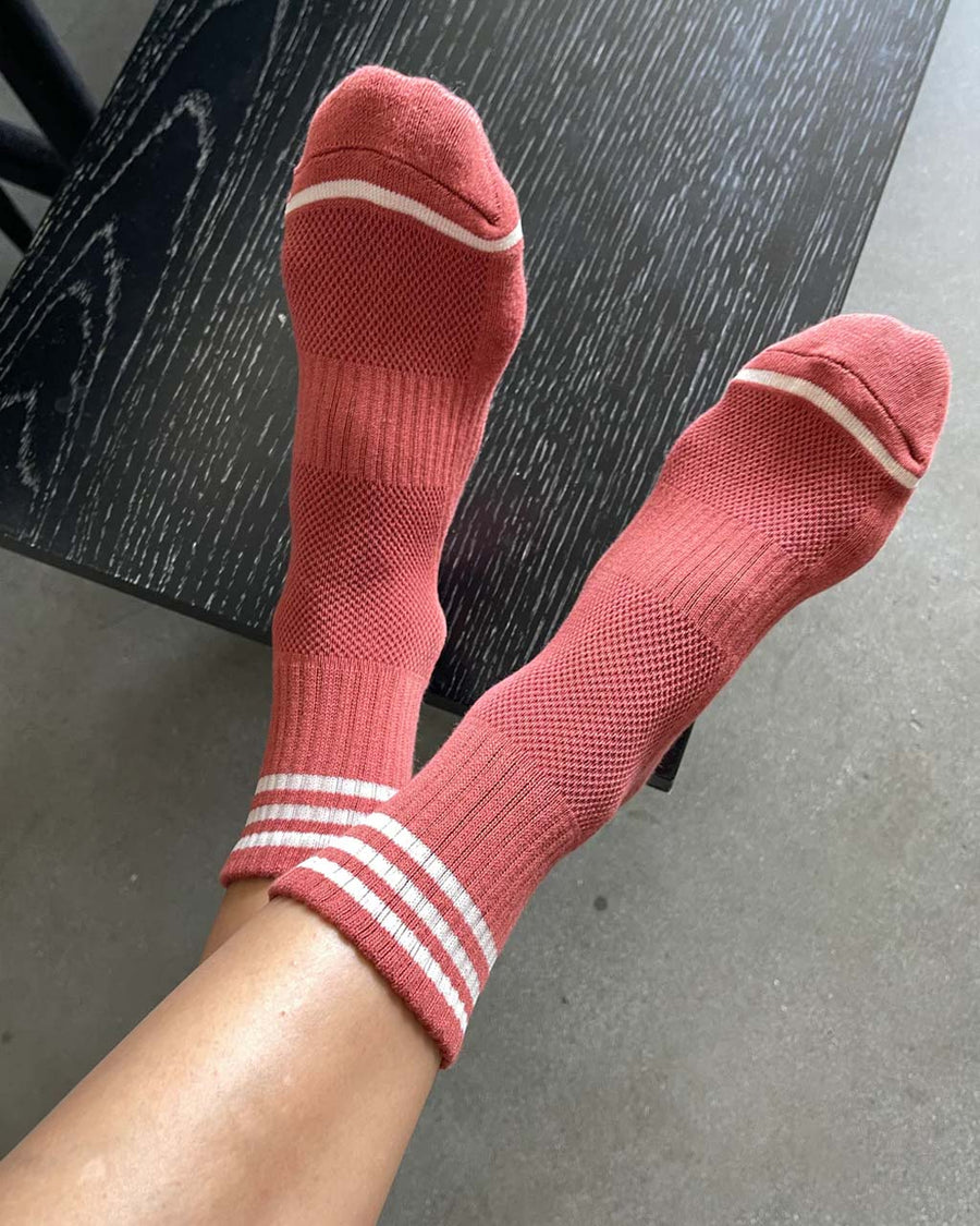 model wearing terracotta high crew socks with three white stripes at the top