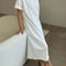 side view of model wearing white short sleeve cotton maxi dress with side slits