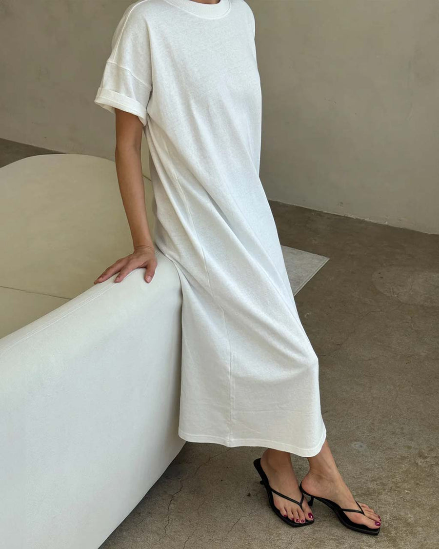 side view of model wearing white short sleeve cotton maxi dress with side slits