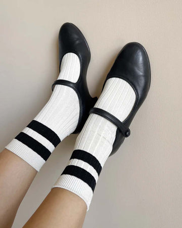 model wearing cream high crew socks with two thick black stripes at the top