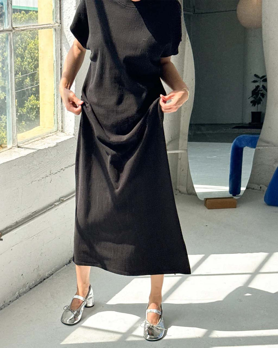 model lifting black maxi dress with slight cap sleeves and side slits