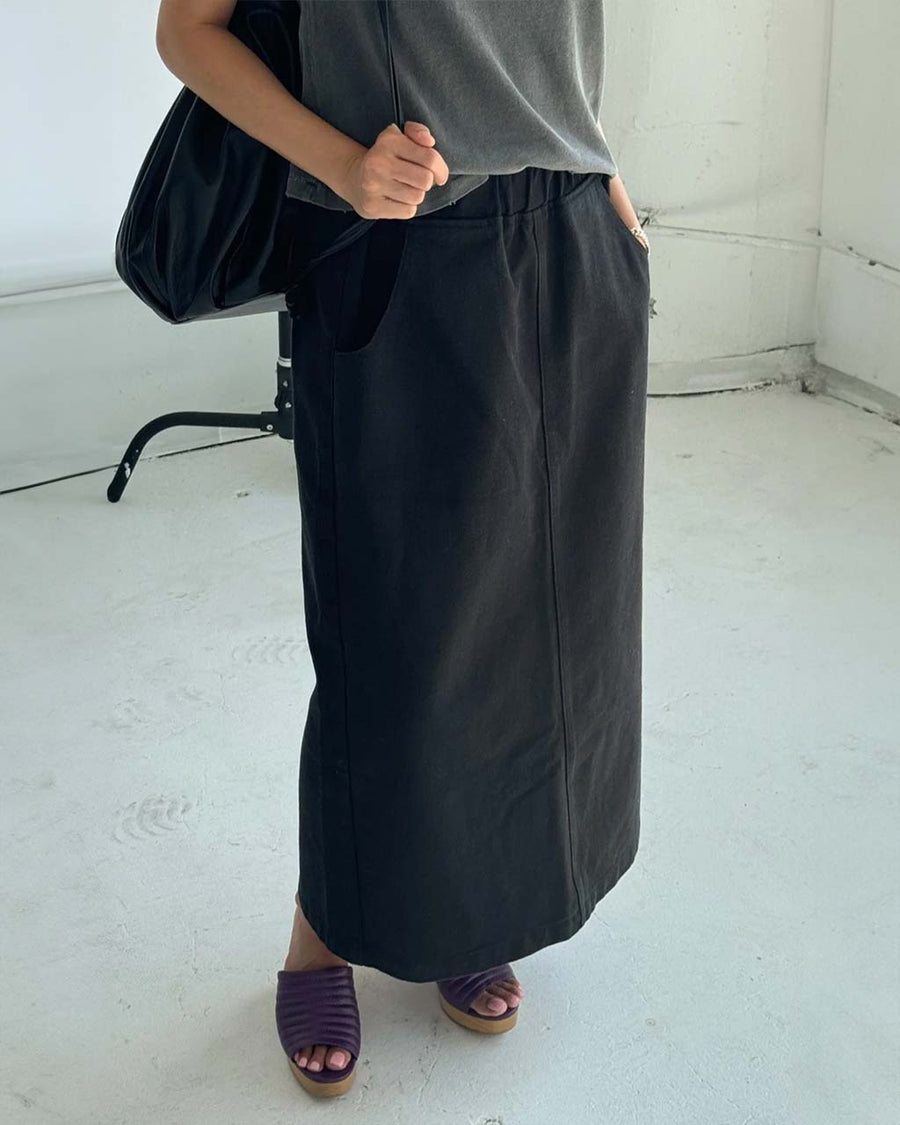 model wearing black long skirt with pockets and slit in the back