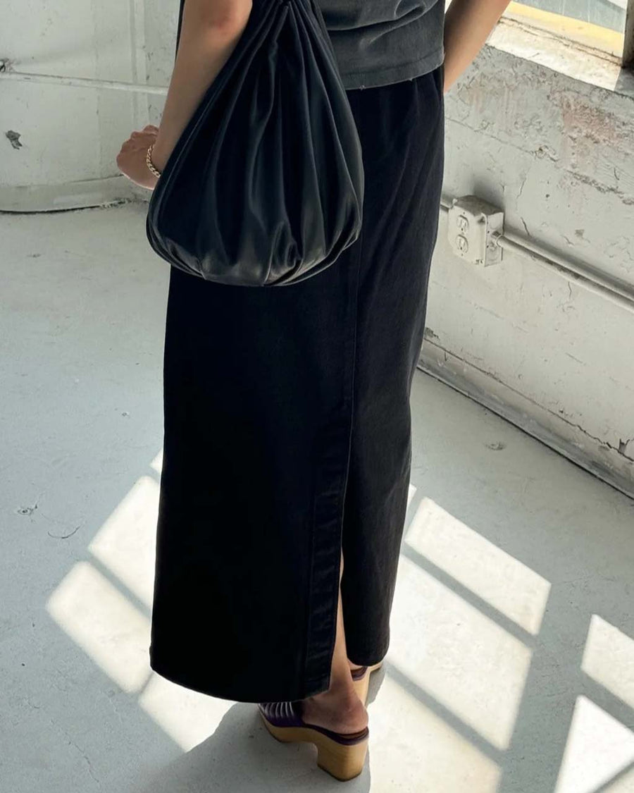 back view of model wearing black long skirt with pockets and slit in the back