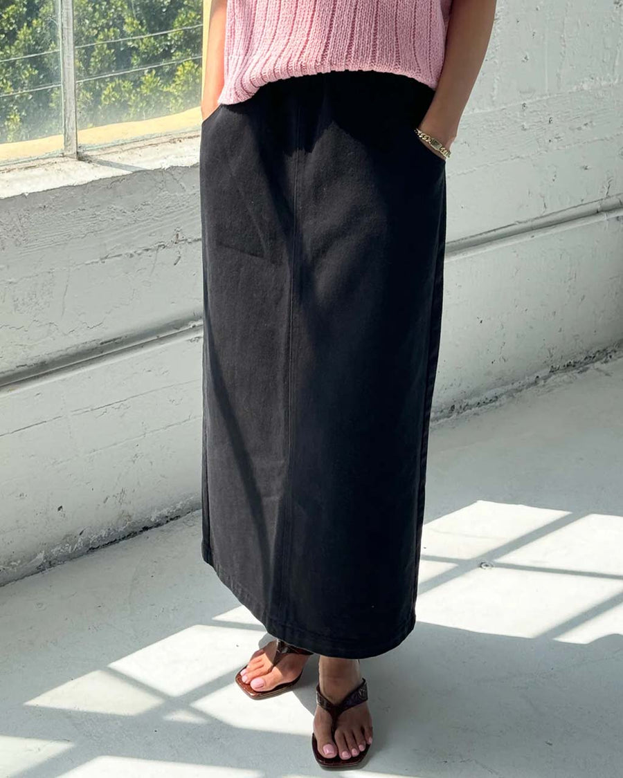 model wearing black long skirt with pockets and slit in the back