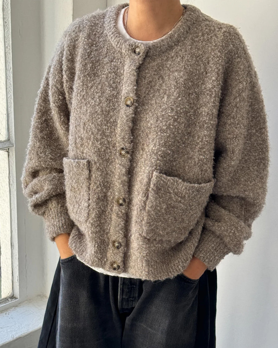 model wearing buttoned taupe boucle cardigan with relaxed fit and front patch pockets