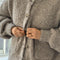 up close of model wearing buttoned taupe boucle cardigan with relaxed fit and front patch pockets