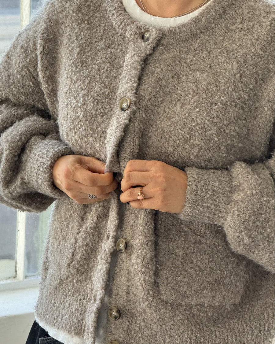 up close of model wearing buttoned taupe boucle cardigan with relaxed fit and front patch pockets