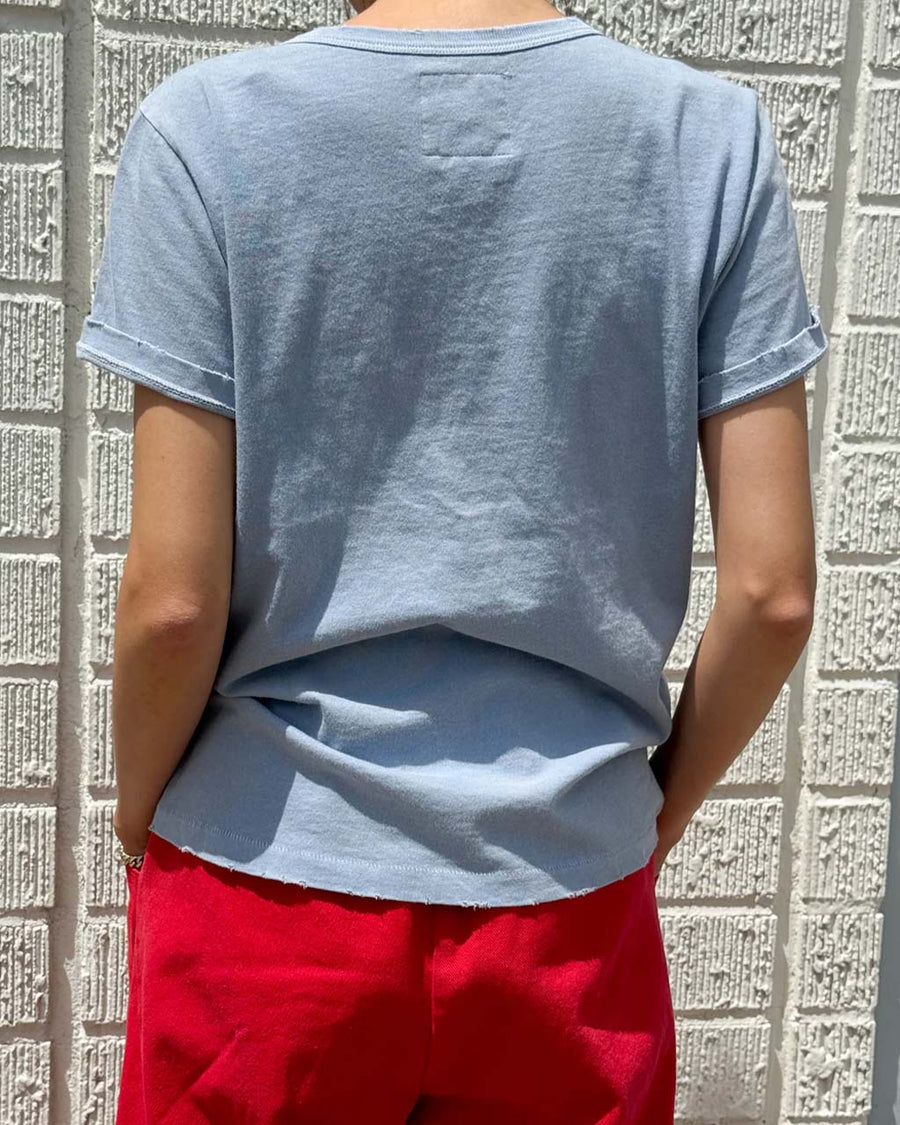 back view of model wearing light blue organic cotton tee with a vintage look and slight distressing on the neckline and arm holes