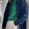 model wearing oversized dark denim button down shirt with striped tee and white pants