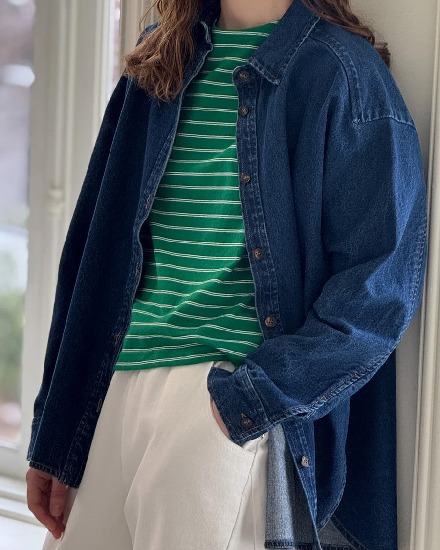 model wearing oversized dark denim button down shirt with striped tee and white pants