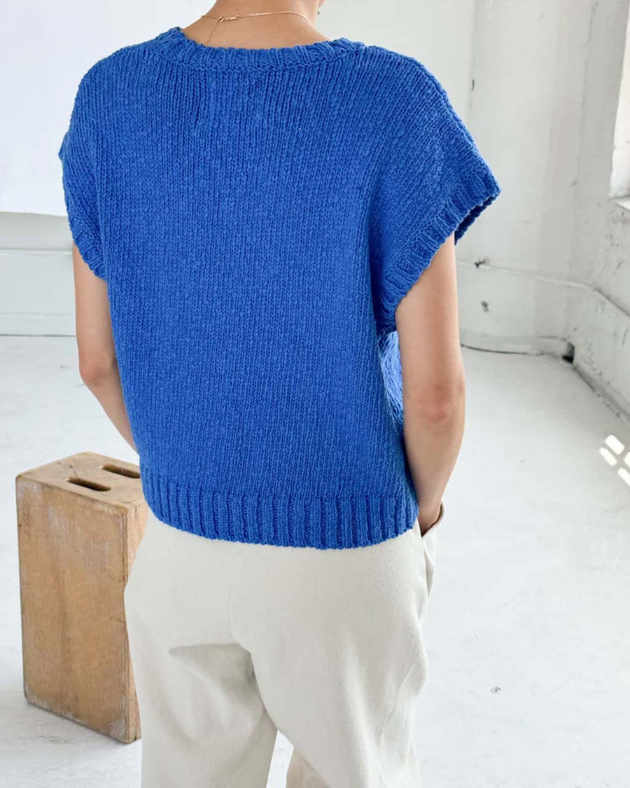 back view of model wearing bright blue sweater top with slight cap sleeves