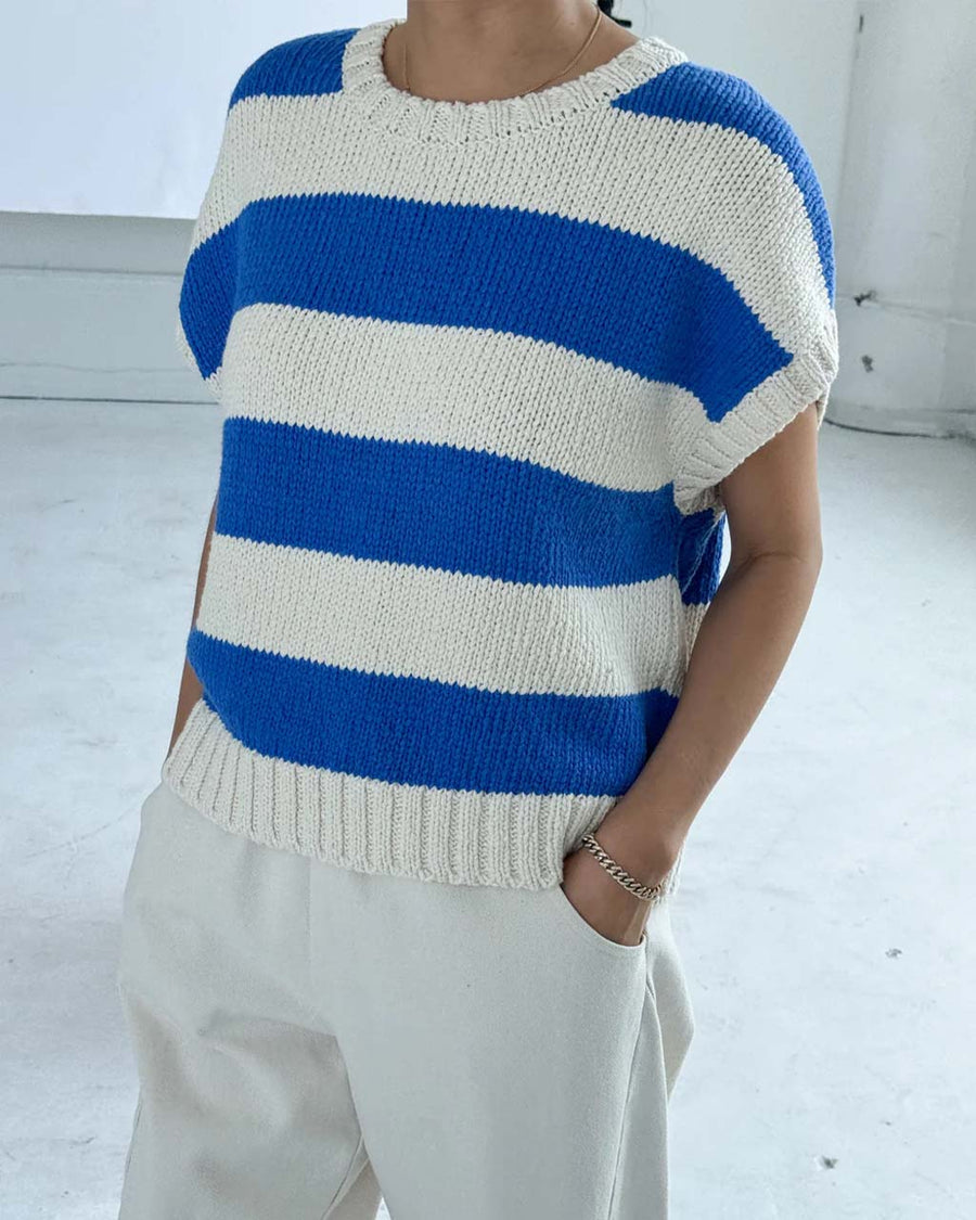 up close of model wearing bright blue and cream striped sweater top with slight cap sleeves